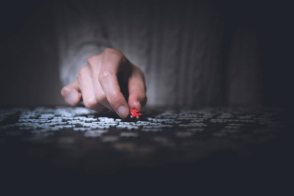 Hand platziert Puzzlestück bei gedämpftem Licht.