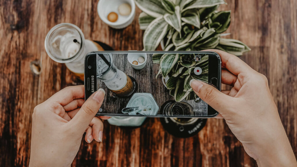 Smartphone fotografiert Pflanze und Getränke.